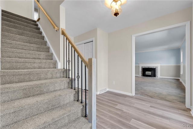 staircase with visible vents, baseboards, wood finished floors, and a fireplace