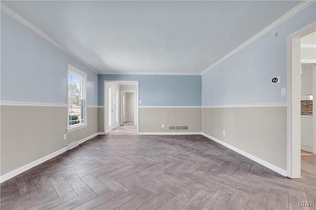 spare room featuring visible vents, crown molding, and baseboards