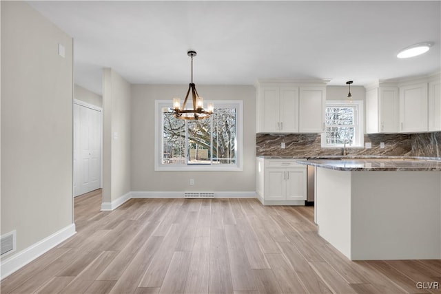 kitchen featuring white cabinetry, dark stone countertops, light wood-style floors, and backsplash