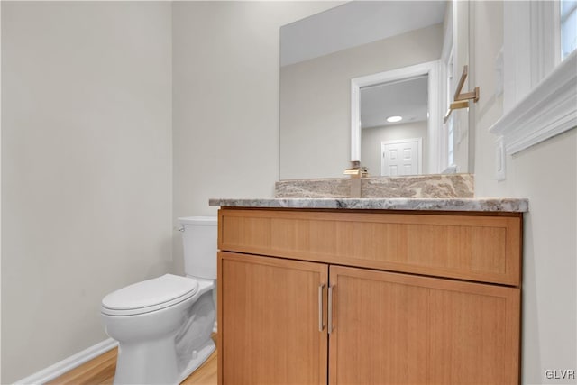 bathroom featuring baseboards, toilet, wood finished floors, and vanity