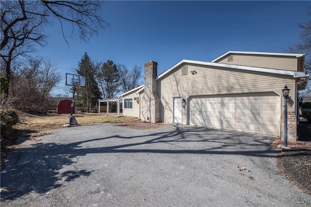 view of property exterior featuring aphalt driveway, a chimney, and a garage