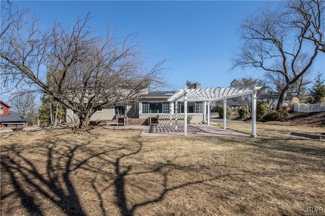 back of house featuring a chimney, a lawn, a pergola, and a patio