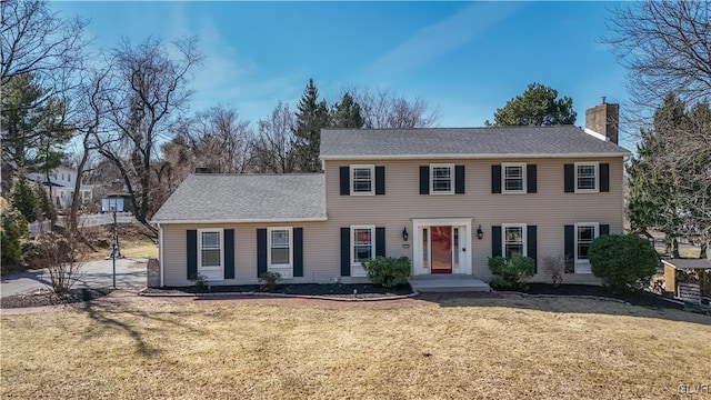 colonial house featuring a front lawn and a chimney