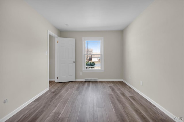 unfurnished room with baseboards, visible vents, and dark wood-style flooring