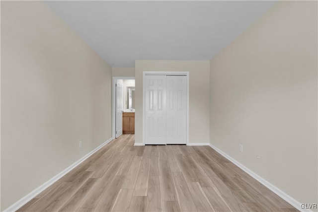 unfurnished bedroom featuring baseboards, light wood-type flooring, and a closet