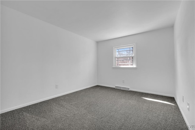 unfurnished room with visible vents, dark carpet, and baseboards