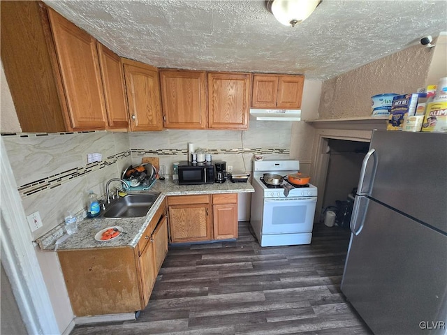 kitchen featuring a sink, under cabinet range hood, freestanding refrigerator, black microwave, and white range with gas stovetop