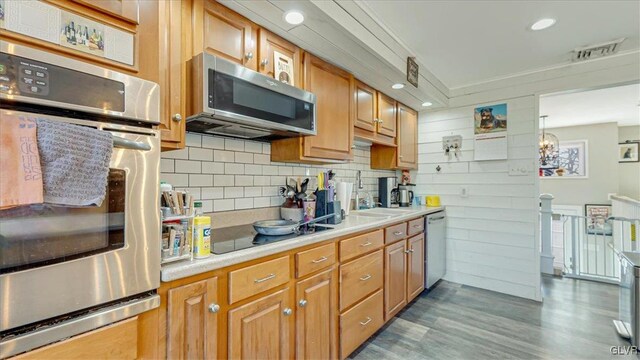 kitchen with visible vents, backsplash, stainless steel appliances, light wood-style floors, and light countertops