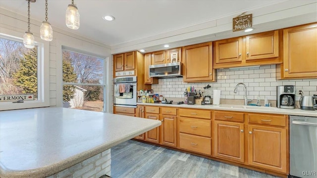 kitchen with light countertops, backsplash, appliances with stainless steel finishes, and a sink