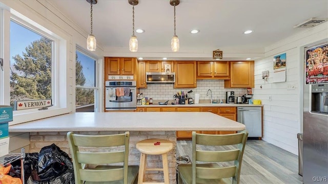 kitchen with visible vents, pendant lighting, backsplash, stainless steel appliances, and light countertops