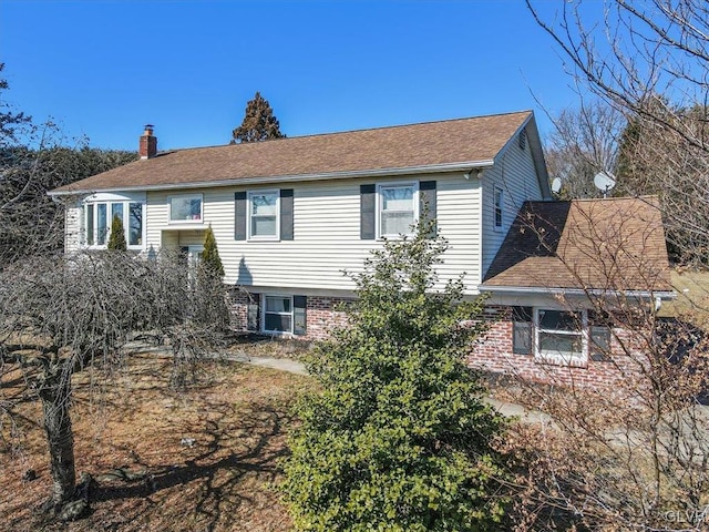 back of house with brick siding and a chimney