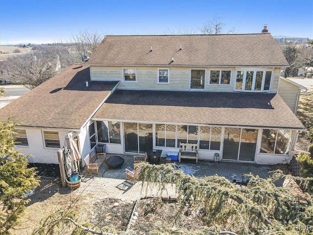 rear view of house featuring a patio area, entry steps, roof with shingles, and a sunroom