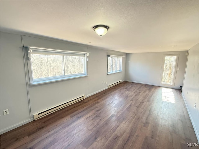 unfurnished room with a baseboard radiator, baseboards, and wood finished floors