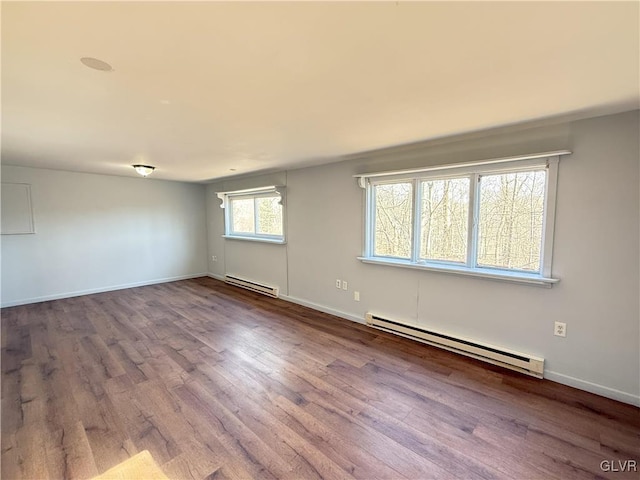 empty room with baseboard heating, baseboards, and wood finished floors