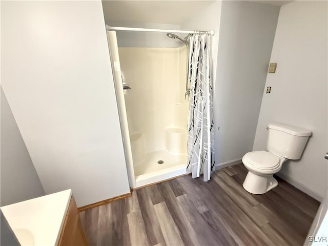 full bathroom featuring vanity, wood finished floors, baseboards, a stall shower, and toilet