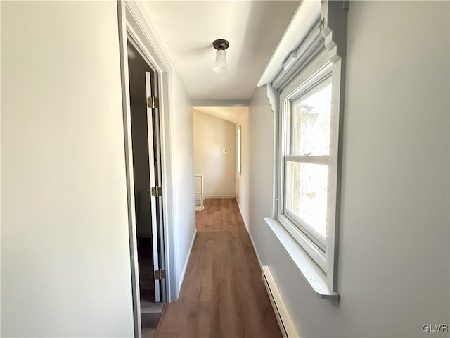 hallway featuring wood finished floors, baseboards, and baseboard heating