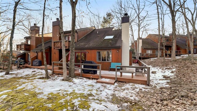 snow covered rear of property with a residential view, a chimney, and a deck