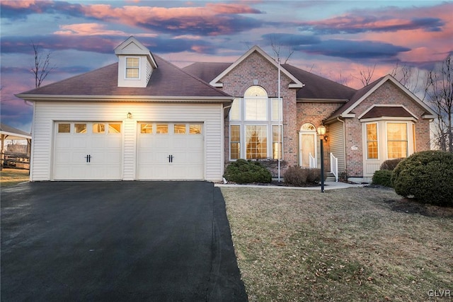 traditional home with aphalt driveway, brick siding, and a garage