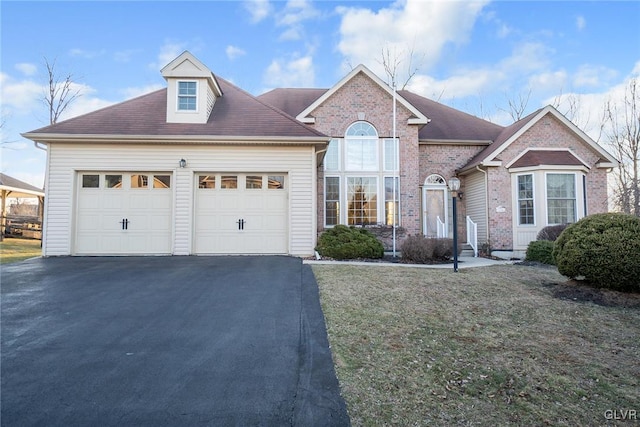 traditional-style home with a front yard, brick siding, a garage, and driveway