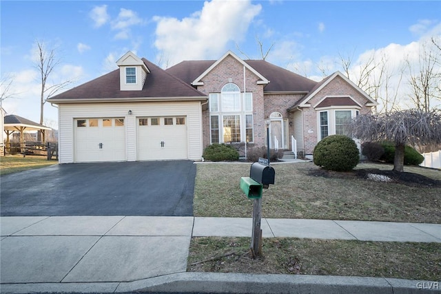 traditional home featuring aphalt driveway, a garage, and brick siding