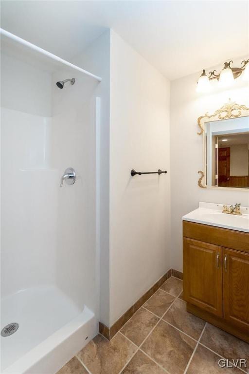 full bathroom featuring vanity, tile patterned floors, baseboards, and a stall shower