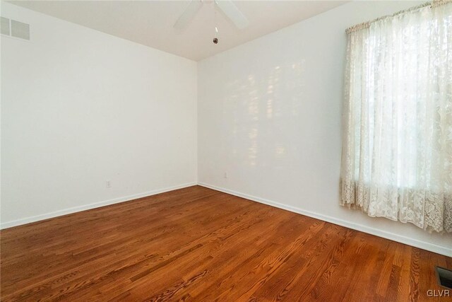 spare room with visible vents, ceiling fan, baseboards, and wood finished floors