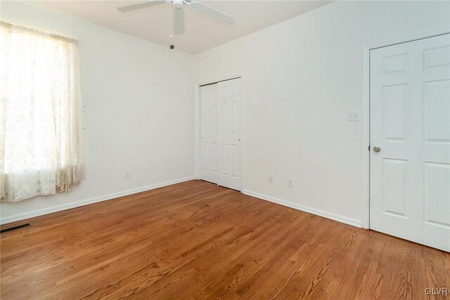 unfurnished room featuring a ceiling fan, wood finished floors, visible vents, and baseboards