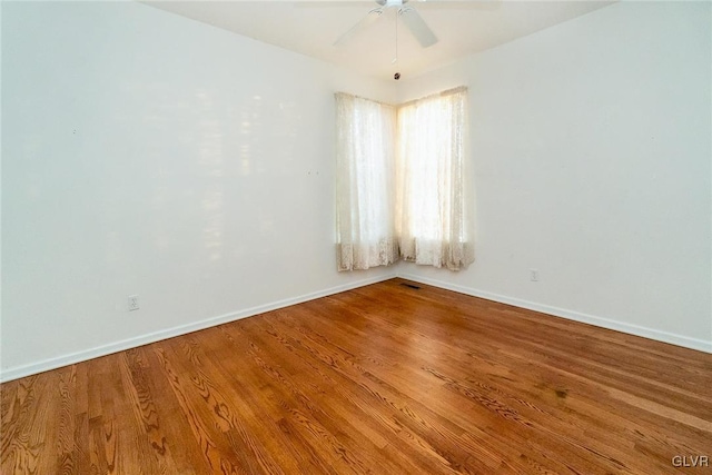 spare room featuring visible vents, a ceiling fan, baseboards, and wood finished floors