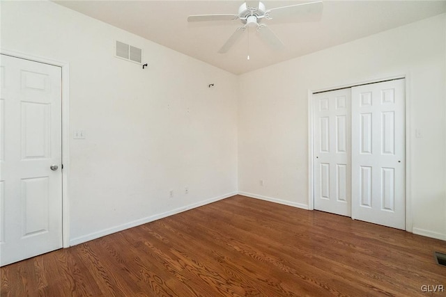 unfurnished bedroom with a closet, visible vents, baseboards, and wood finished floors