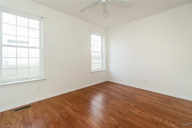 spare room with ceiling fan, wood finished floors, visible vents, and baseboards