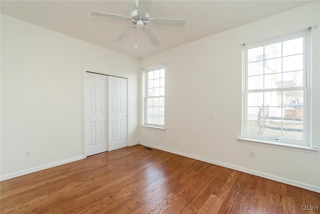 unfurnished bedroom with visible vents, wood finished floors, baseboards, and a closet