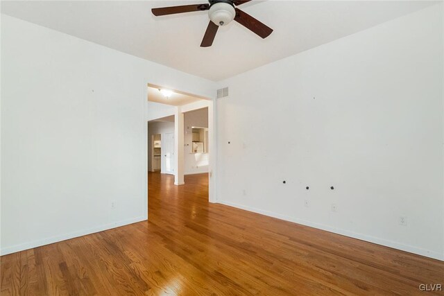 spare room featuring visible vents, a ceiling fan, baseboards, and wood finished floors