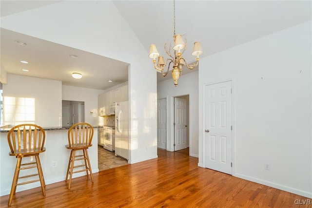 unfurnished dining area with baseboards, a chandelier, vaulted ceiling, recessed lighting, and light wood-style flooring