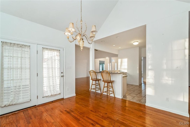 interior space featuring vaulted ceiling, a notable chandelier, light wood-type flooring, and a wealth of natural light