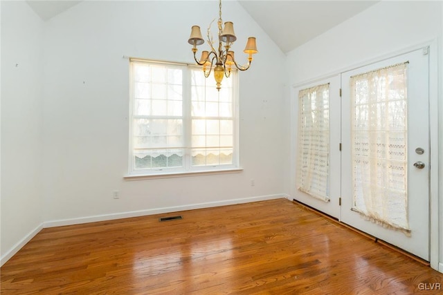 interior space featuring lofted ceiling, wood finished floors, visible vents, and baseboards