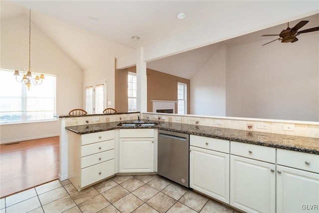 kitchen with a sink, white cabinets, light tile patterned floors, dishwasher, and vaulted ceiling