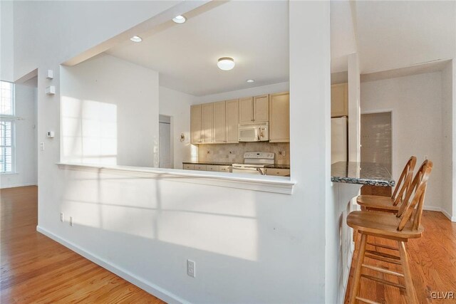 kitchen with tasteful backsplash, wood finished floors, recessed lighting, white appliances, and baseboards