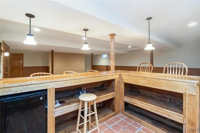 interior space with wet bar, tile patterned floors, hanging light fixtures, and a wainscoted wall