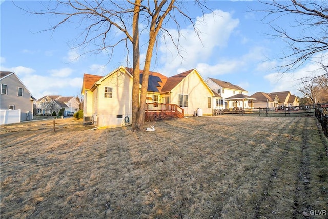 rear view of property featuring a residential view, a lawn, a deck, and fence