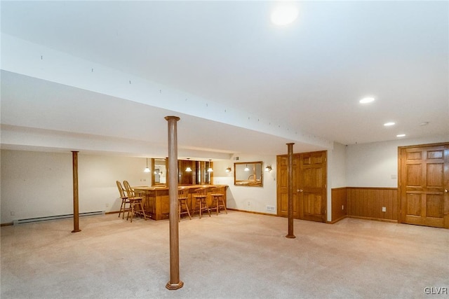 finished basement with a baseboard heating unit, a dry bar, carpet, and a wainscoted wall