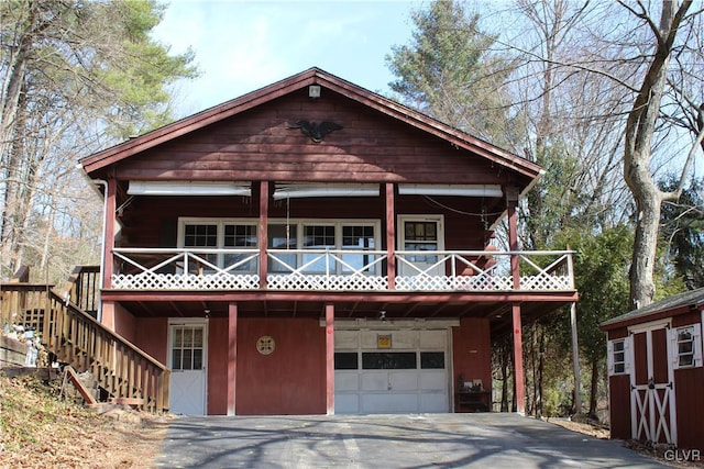 chalet / cabin featuring stairway, concrete driveway, a storage shed, a garage, and an outbuilding