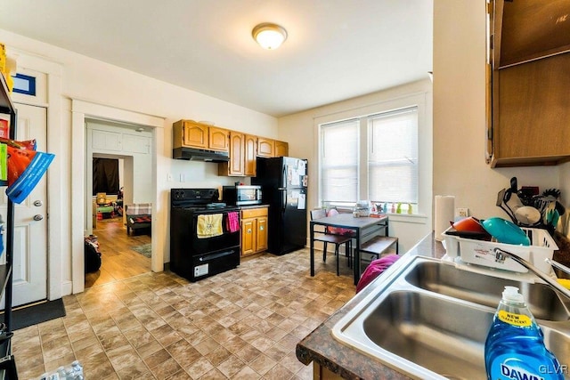 kitchen featuring black appliances, brown cabinetry, under cabinet range hood, and a sink