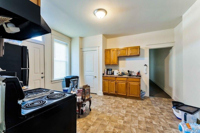 kitchen with ventilation hood, baseboards, light countertops, brown cabinetry, and black appliances