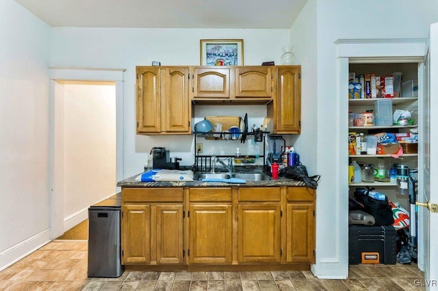 kitchen with a sink, brown cabinets, and dark countertops