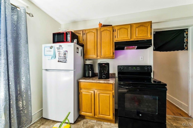 kitchen with brown cabinetry, baseboards, electric range, freestanding refrigerator, and under cabinet range hood