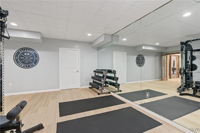 workout area with a drop ceiling, recessed lighting, baseboards, and wood finished floors