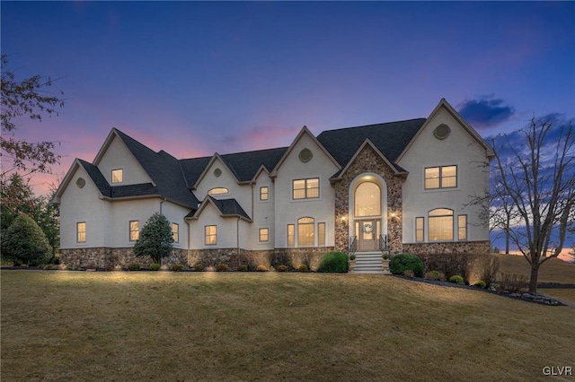 french country style house featuring a yard, stone siding, and stucco siding