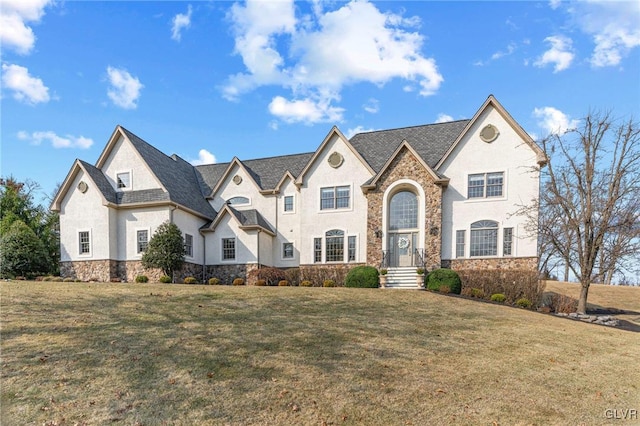 french country style house with a front lawn, stone siding, and stucco siding