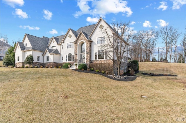 view of front of home with a front yard, stone siding, and stucco siding