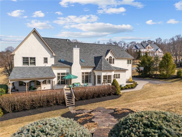 back of property featuring stairway, stucco siding, and a shingled roof